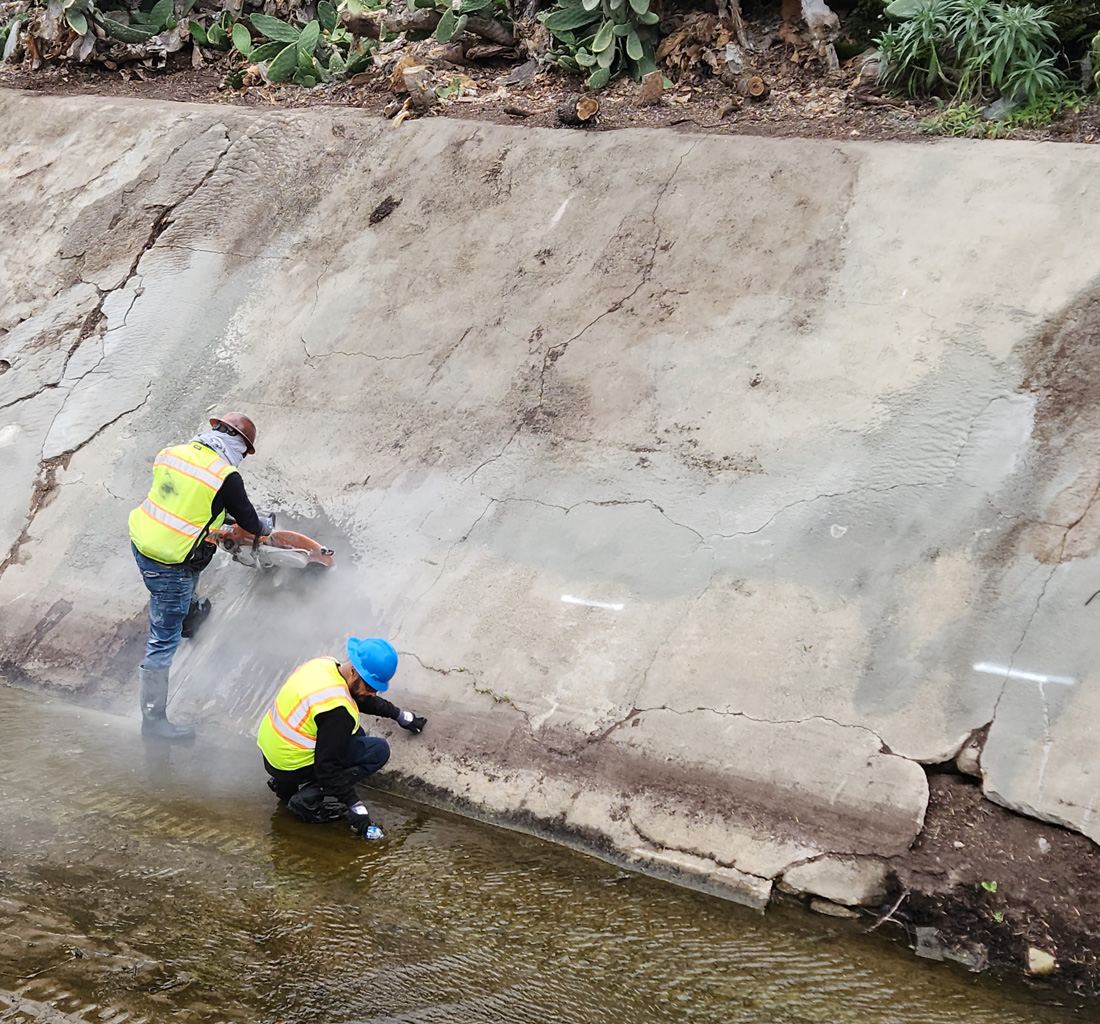 Workers fixing a cracked stormwater channel
